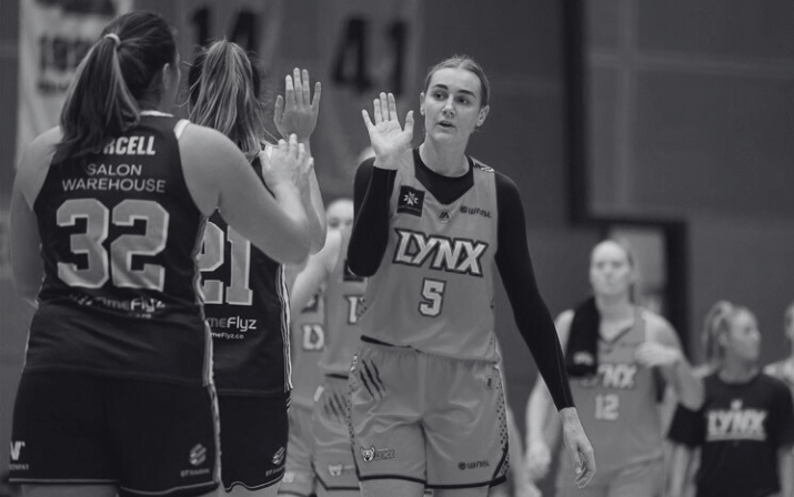 Black and white photo of Darcee Garbin high fiving two teammates at Bendat Basketball Centre in Floreat, Perth